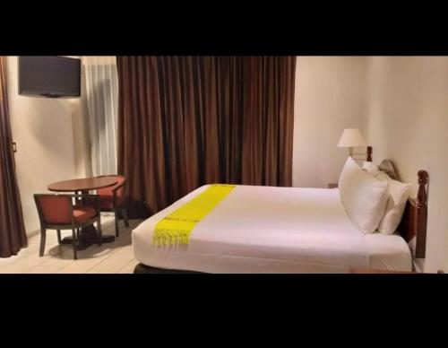 um quarto de hotel com uma cama e uma mesa em HOTEL REAL FLOR DE MARIA em Comitán de Domínguez