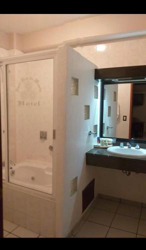 uma casa de banho com uma banheira, um lavatório e um espelho. em HOTEL REAL FLOR DE MARIA em Comitán de Domínguez