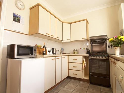 a kitchen with white cabinets and a microwave at 2 bed property in Wooler Northumberland CN226 in Wooler
