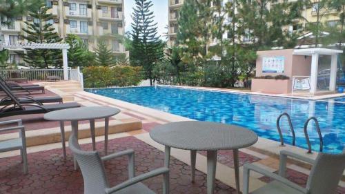 達沃市的住宿－1608 Three Bedrooms With 1 free parking, swimming pool WiFi and Netflix at Northpoint Camella Condominium Bajada Davao City，一座带桌椅的游泳池位于大楼旁