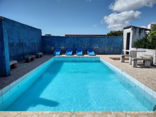una piscina con due sedie blu e un muro di Casa Temporada Prainha - Aquiraz ad Aquiraz