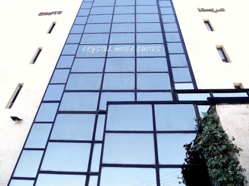 a tall glass building with a plant in front of it at Crystal Suites in Amman