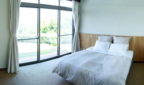 Seaside Villa SASAO - Vacation STAY 33407v في Sanuki: غرفة نوم بسرير ونافذة كبيرة