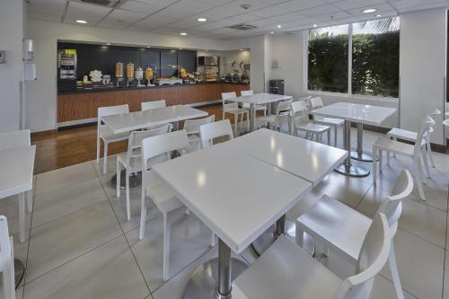 a restaurant with white tables and white chairs at City Express by Marriott Chetumal in Chetumal