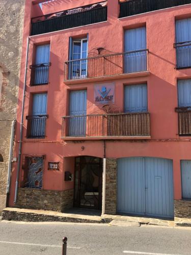 un edificio rojo con puertas azules y balcón en Centre de Collioure Appartement tout confort 2-4 pers avec climatisation et wifi classé 2 étoiles, en Collioure