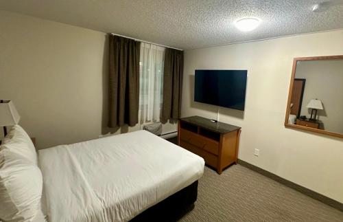 a hotel room with a bed and a flat screen tv at Anavada Inn & Suites - Grande Prairie in Grande Prairie