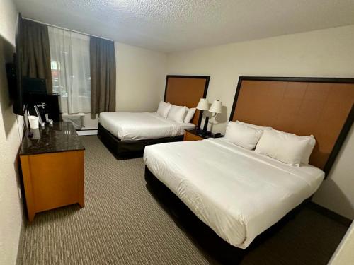 a hotel room with two beds and a television at Anavada Inn & Suites - Grande Prairie in Grande Prairie