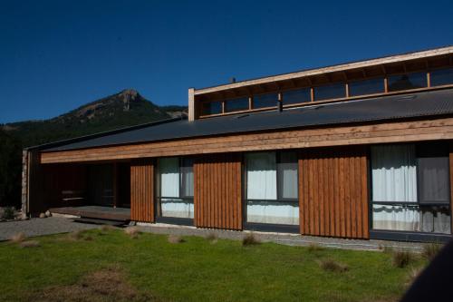 a house with wooden facade with a mountain in the background at Calma Sur Hoteleria Boutique in Villa Meliquina