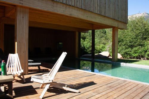 two chairs sitting on a deck next to a swimming pool at Calma Sur Hoteleria Boutique in Villa Meliquina