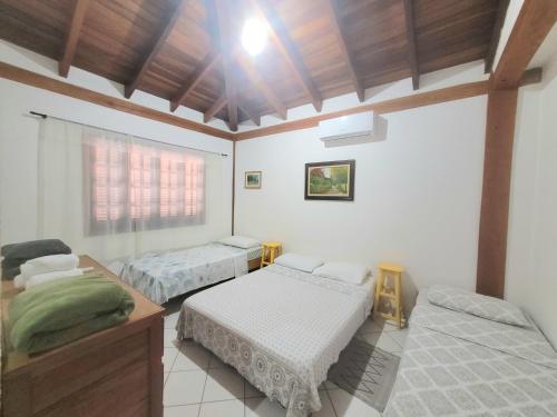 Habitación con 2 camas, mesa y ventana en Casa para temporada em Ilhabela, en Ilhabela