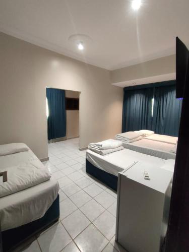 a hotel room with two beds with blue curtains at دانيال للشقق المفروشة in Al Madinah