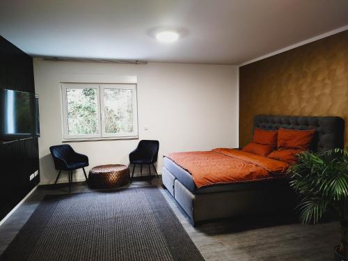 - une chambre avec un lit doté d'oreillers orange et de 2 chaises dans l'établissement Valley of Business Frankfurt-West - Studio Apartment, à Hofheim am Taunus