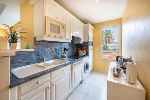 une cuisine avec des armoires blanches et un évier dans l'établissement Cannes banane beau 2 pièces, à Cannes