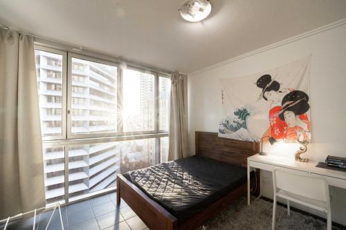 a bedroom with a bed and a desk and a window at Prime location - CBD Brisbane 1 bed w shared 25m pool, gym, sundeck and a BBQ area in Brisbane