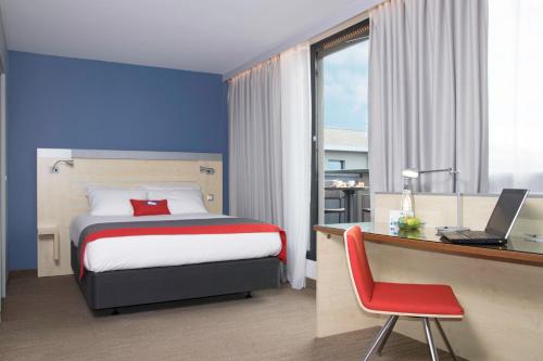 a bedroom with a bed and a desk with a laptop at Holiday Inn Express Toulouse Airport, an IHG Hotel in Blagnac