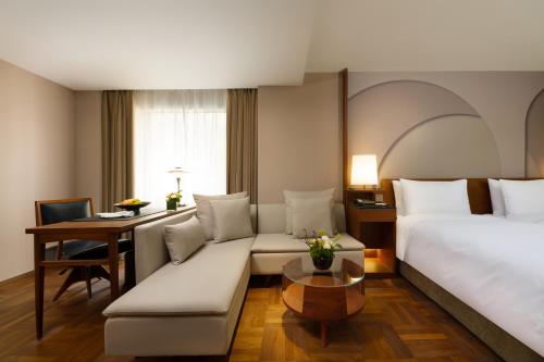 a hotel room with a couch and a bed and a table at Maxx by Steigenberger on the Bund Shanghai in Shanghai