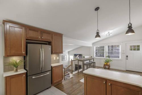 a kitchen with wooden cabinets and a stainless steel refrigerator at 2BR 2Bath Chamblee Brookhaven Ashford Park Brand new furnishings throughout in Atlanta