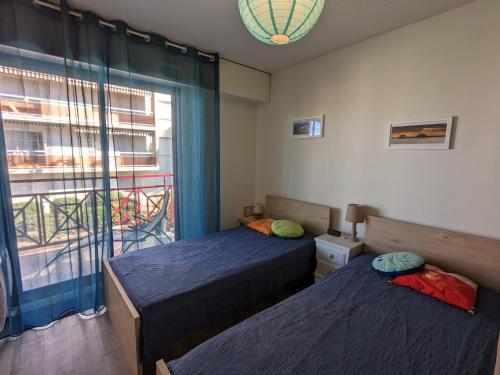 deux lits dans une chambre avec une fenêtre dans l'établissement Arcachon - Ville d'Automne: Agréable T3 pour 4 avec Balcon, Parking et Proche Plage - FR-1-420-30, à Arcachon