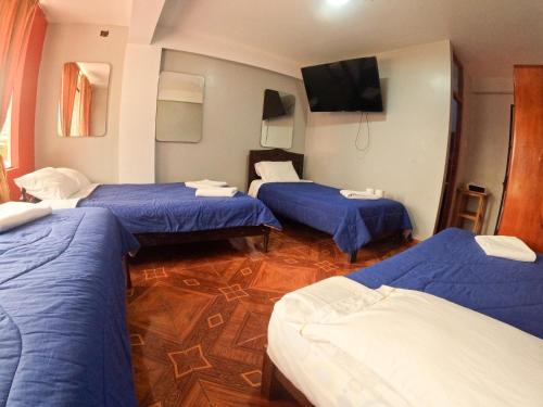 een kamer met 3 bedden en een flatscreen-tv bij Hospedaje Piura in Oxapampa