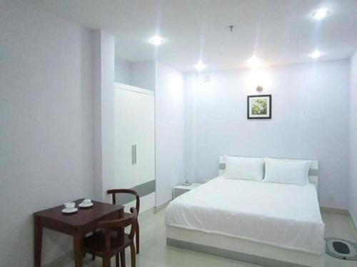 ein weißes Schlafzimmer mit einem Bett und einem Tisch in der Unterkunft Lê Đại Phát Hotel - 498 An Dương Vương ,Q6 - by Bay Luxury in Ho-Chi-Minh-Stadt