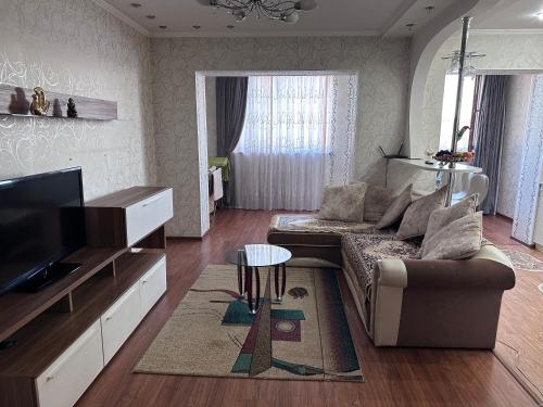 a living room with a couch and a tv at Квартира посуточно in Shymkent