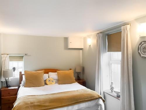 een slaapkamer met een bed met gele kussens en een raam bij Chesterton Cottage in Miningsby