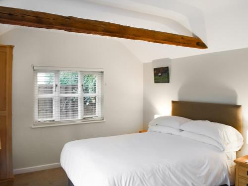 1 dormitorio con cama blanca y ventana en The Six Bells Barn, en Sudbury