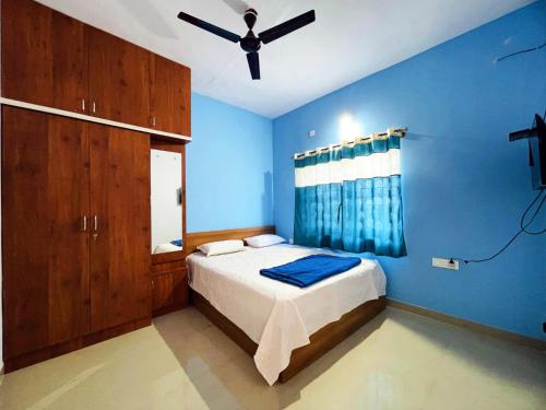 1 dormitorio azul con 1 cama y ventilador de techo en Dhruva Service Apartment en Bidadi