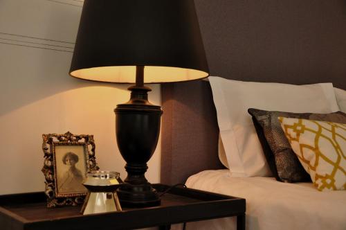 a lamp on a table next to a bed at Casa18.55 - Time with history in São Brás de Alportel