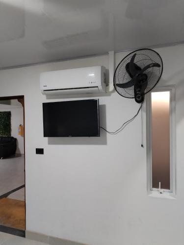 Habitación con TV y ventilador en la pared. en Hotel Ariza Real en Saravena