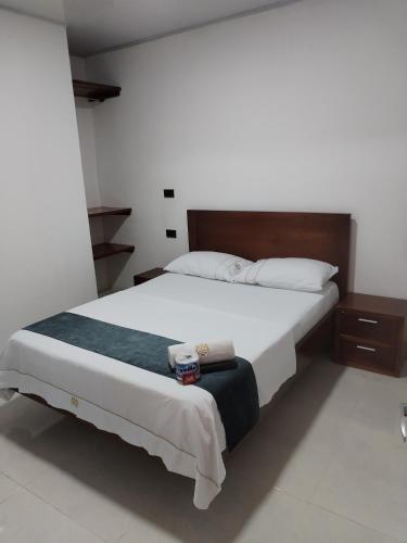 um quarto com uma cama grande e lençóis brancos em Hotel Ariza Real em Saravena