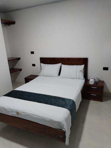 a bedroom with a large bed with white sheets at Hotel Ariza Real in Saravena