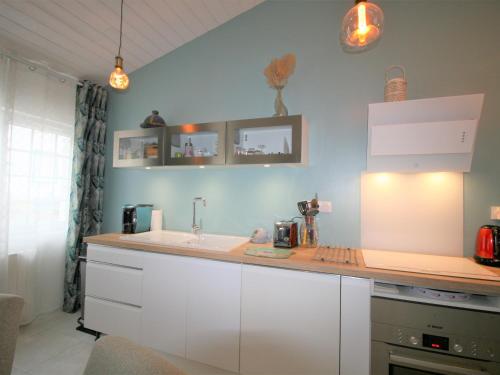 une cuisine avec des armoires blanches et un évier dans l'établissement Maison rénovée à La Tranche-sur-Mer, proche plages et commerces, pour 4 personnes - FR-1-22-300, à La Tranche-sur-Mer