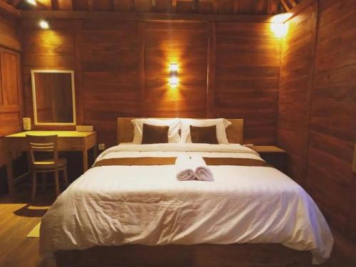 1 dormitorio con 1 cama blanca grande y paredes de madera en Bharata Beach House, en Keramas