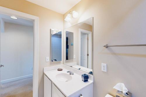een witte badkamer met een wastafel en een spiegel bij Millville by the Sea --- 33504 Belvedere St in Millville