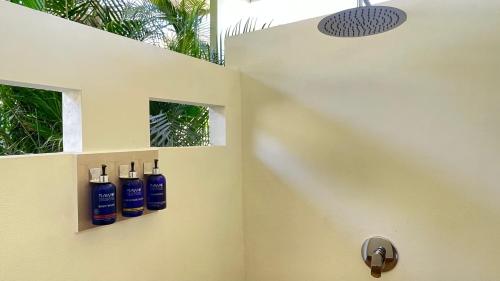 a bathroom with three blue bottles on the wall at Casitas Sollevante Boutique Hotel in Montezuma