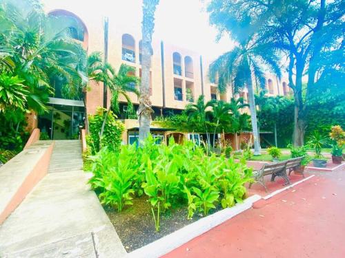 a building with a bench and plants in front of it at Villa Caribe Cancún in Cancún