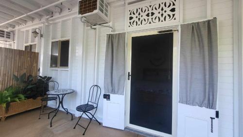 a porch with two chairs and a table and a door at Ribbonwood Bed & Breakfast, Emu Park Qld in Emu Park