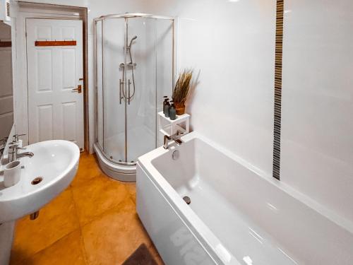 a bathroom with a shower and a tub and a sink at Rothsay Beach House in Newbiggin-by-the-Sea