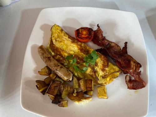 a plate of breakfast food with eggs bacon and potatoes at Suwehan Beach Cliff House by BIJAK in Polilit