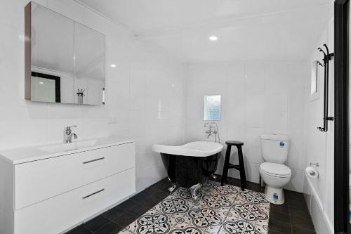 La salle de bains blanche est pourvue d'un lavabo et de toilettes. dans l'établissement Retro on walker, à Maryborough