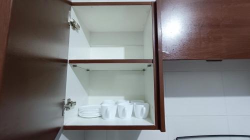 ein Badezimmer mit weißen Tassen und Tellern auf einem Regal in der Unterkunft Elegante y Céntrico depto próximo al Prado in Cochabamba