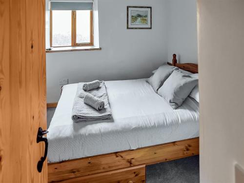 a bedroom with a bed with white sheets and a window at Mill Meadow Cottage in East Down