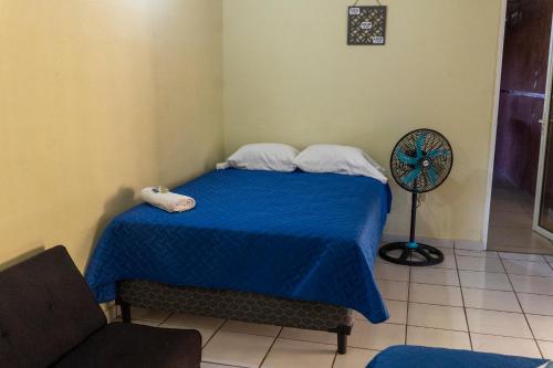 Schlafzimmer mit einem Bett mit blauer Bettwäsche und einem Ventilator in der Unterkunft Villa La Casita in Santa Ana