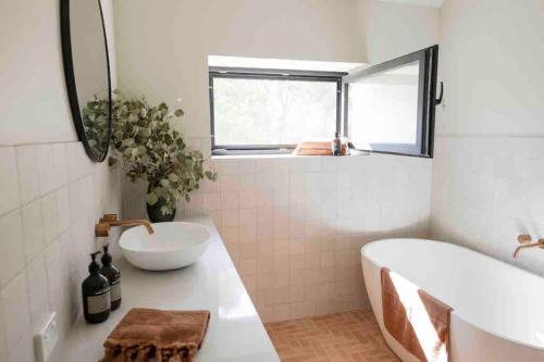 ein Badezimmer mit einer Badewanne, einem Waschbecken und einem Spiegel in der Unterkunft Gardeners Shed -Mansfield in Mansfield
