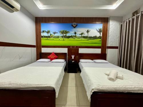 two beds in a room with a painting on the wall at Khách Sạn Hoàng Hà in Ho Chi Minh City