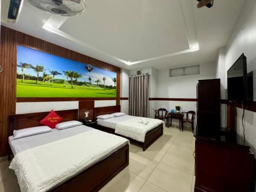 a hotel room with two beds and a flat screen tv at Khách Sạn Hoàng Hà in Ho Chi Minh City