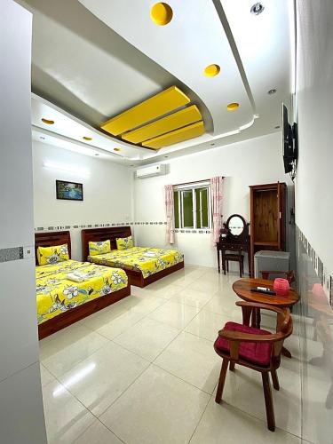 a room with two beds and a table and a tableasteryasteryasteryasteryastery at Ngoc May Guesthouse in Chau Doc