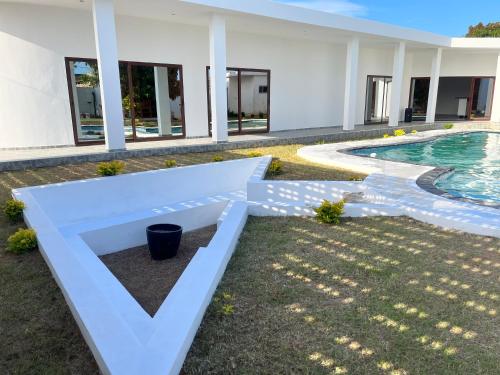 a white house with a pool and a yard at Txumas in Maputo