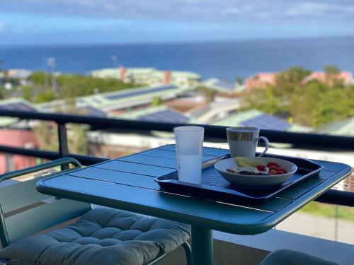a blue table with a bowl of fruit and drinks on a balcony at Appart sympa, vue sur le lagon à Saint-Gilles les bains in Saint-Gilles les Bains